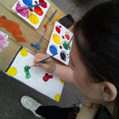 Young person painting blobs in red, yellow and green